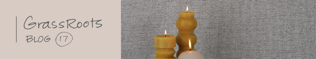 Bee's wax candles in from of soft gray woven wallpaper.